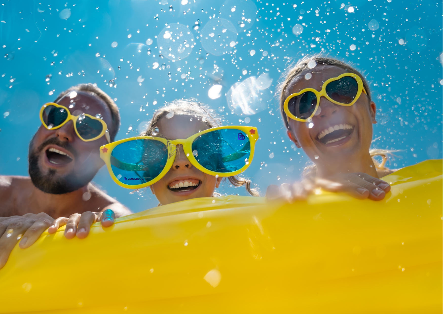 A smiling family wearing yellow sunglasses enjoys a water ride.