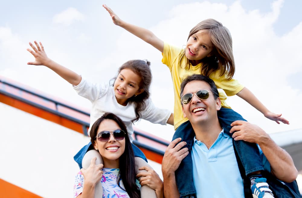 Image shows family. Two children on the shoulders of their parents.